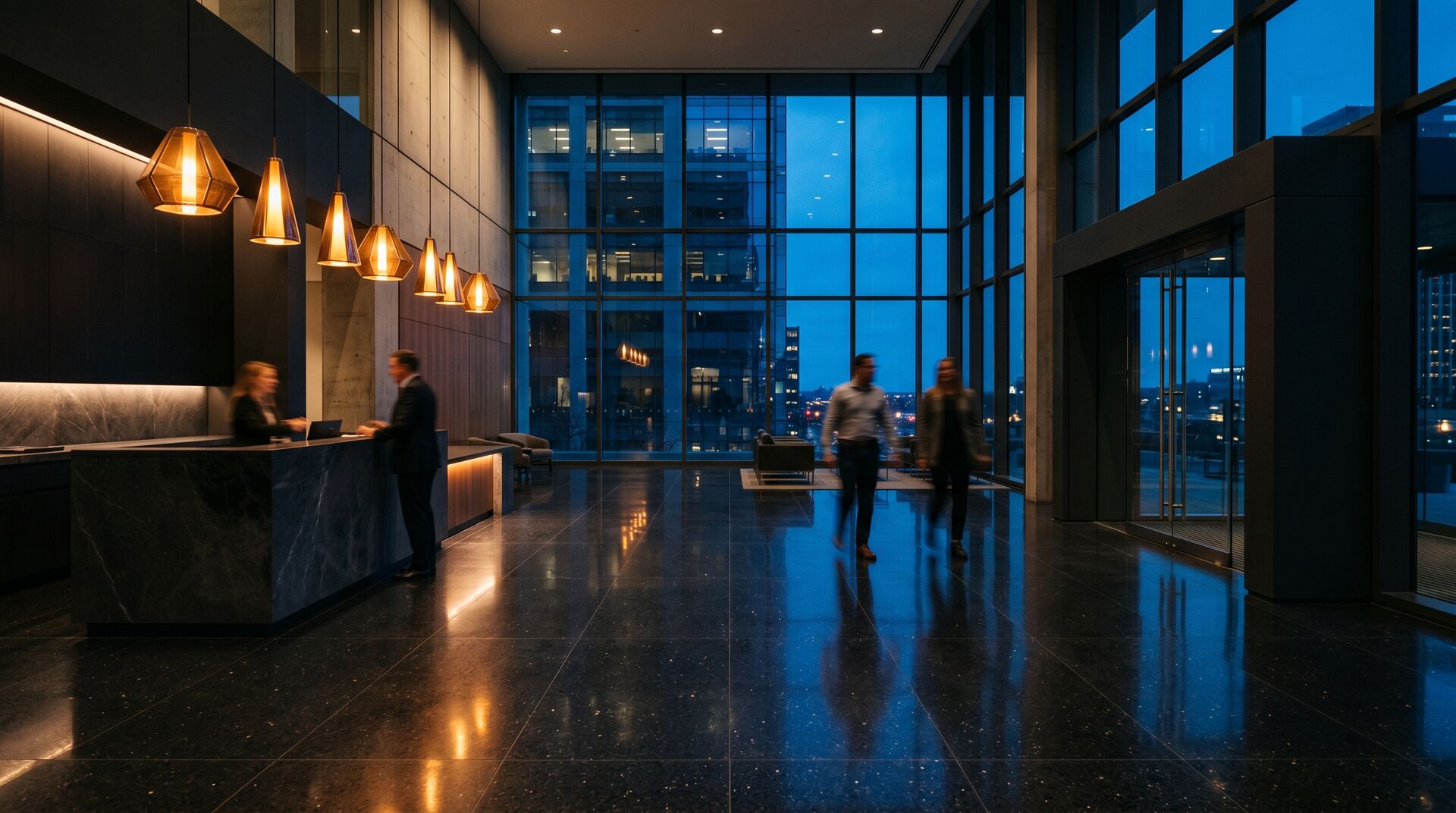 Modern building lobby at dusk with warm pendant lighting and occupants